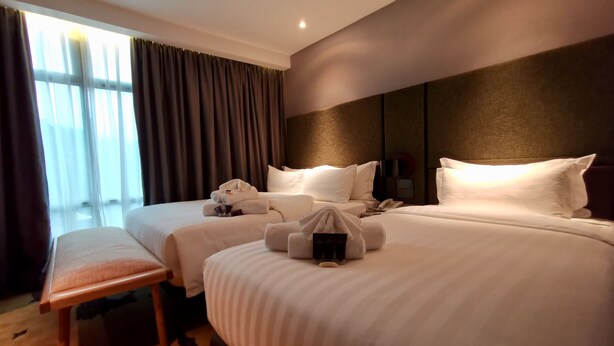 A hotel room with two beds, a bench, and a large window with curtains. - King Park Hotel Kota Kinabalu (Kota Kinabalu)