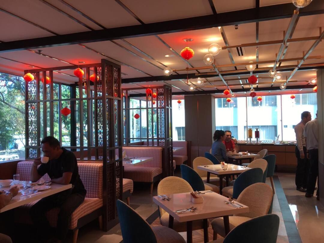 A restaurant with booths and tables, red lanterns hanging from the ceiling, and a view of the outdoors through large windows.