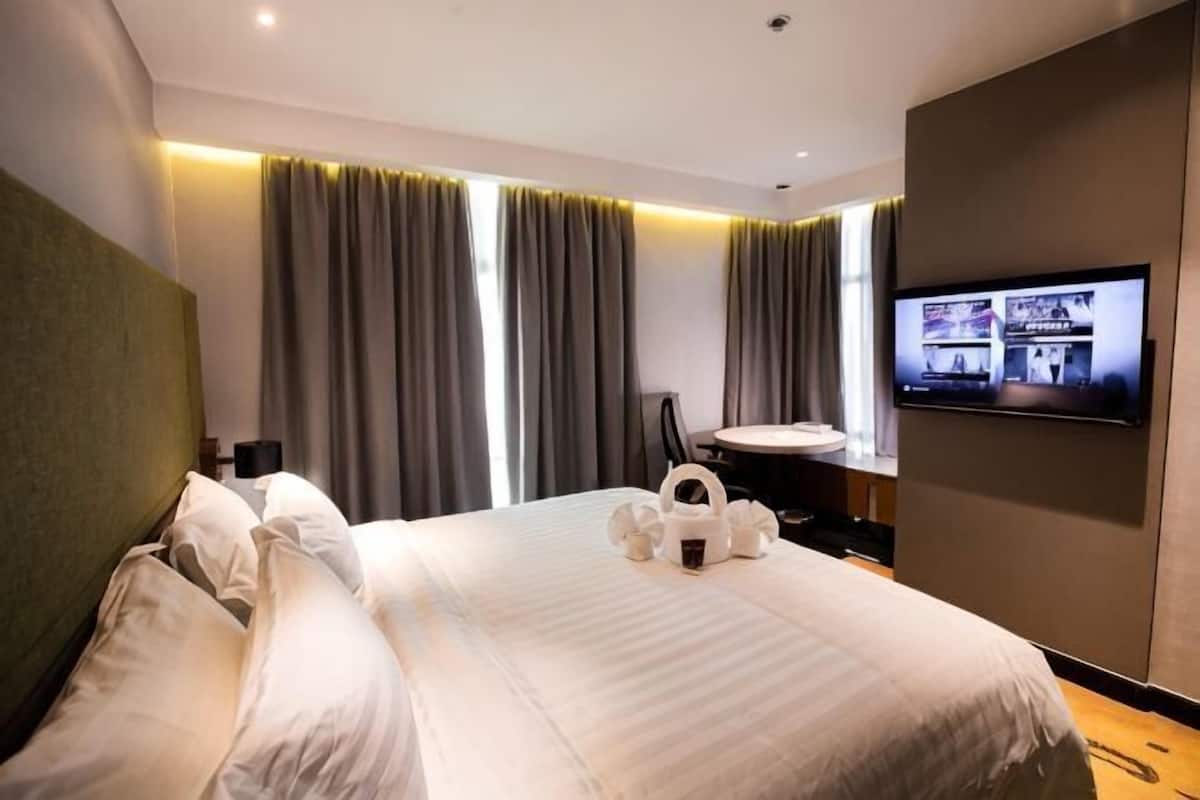 Habitación de hotel con una cama grande, un televisor de pantalla plana en la pared y un escritorio con una silla.