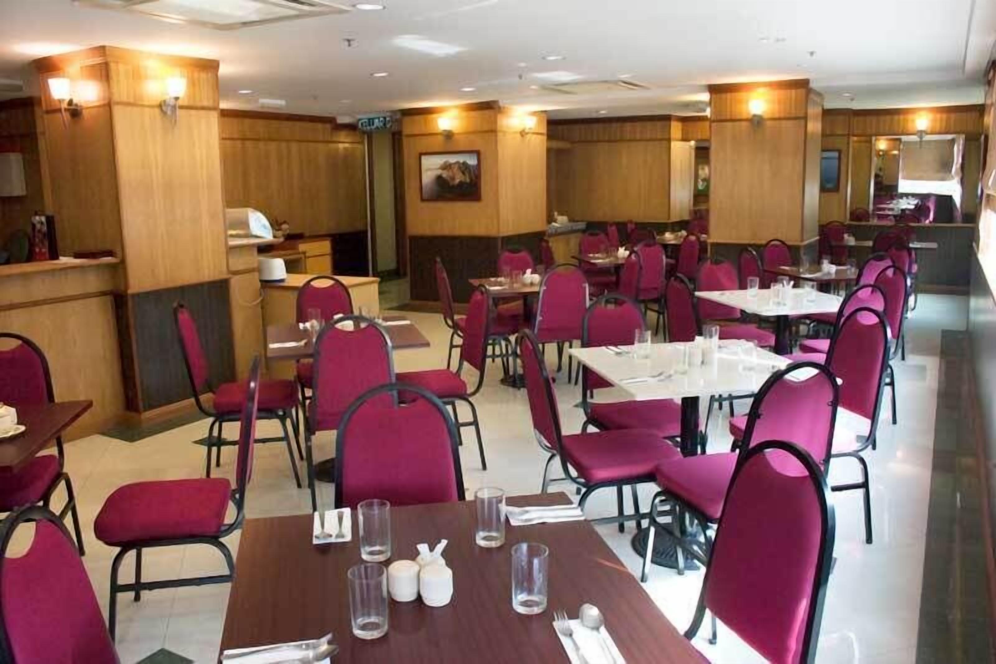 A restaurant with tables and chairs, wooden paneling, and a painting on the wall.