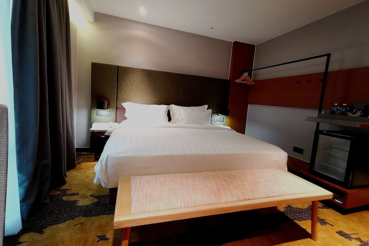Habitación de hotel con una cama grande, mesitas de noche, un escritorio, una silla, un armario y un televisor.