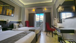 Een hotelkamer met twee bedden, een bureau, een stoel, een televisie en een balkon met uitzicht.