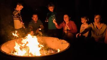 Un grupo de personas reunidas alrededor de una fogata en un entorno oscuro al aire libre.