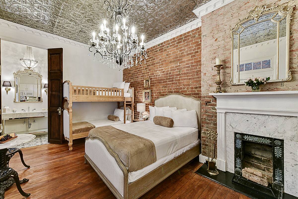 A bedroom with a wooden bunk bed, a white fireplace, and a chandelier.