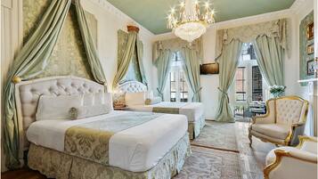 Ein luxuriöses Schlafzimmer mit einem großen Bett, zwei Einzelbetten, einer Chandelüster und klassischer Einrichtung.