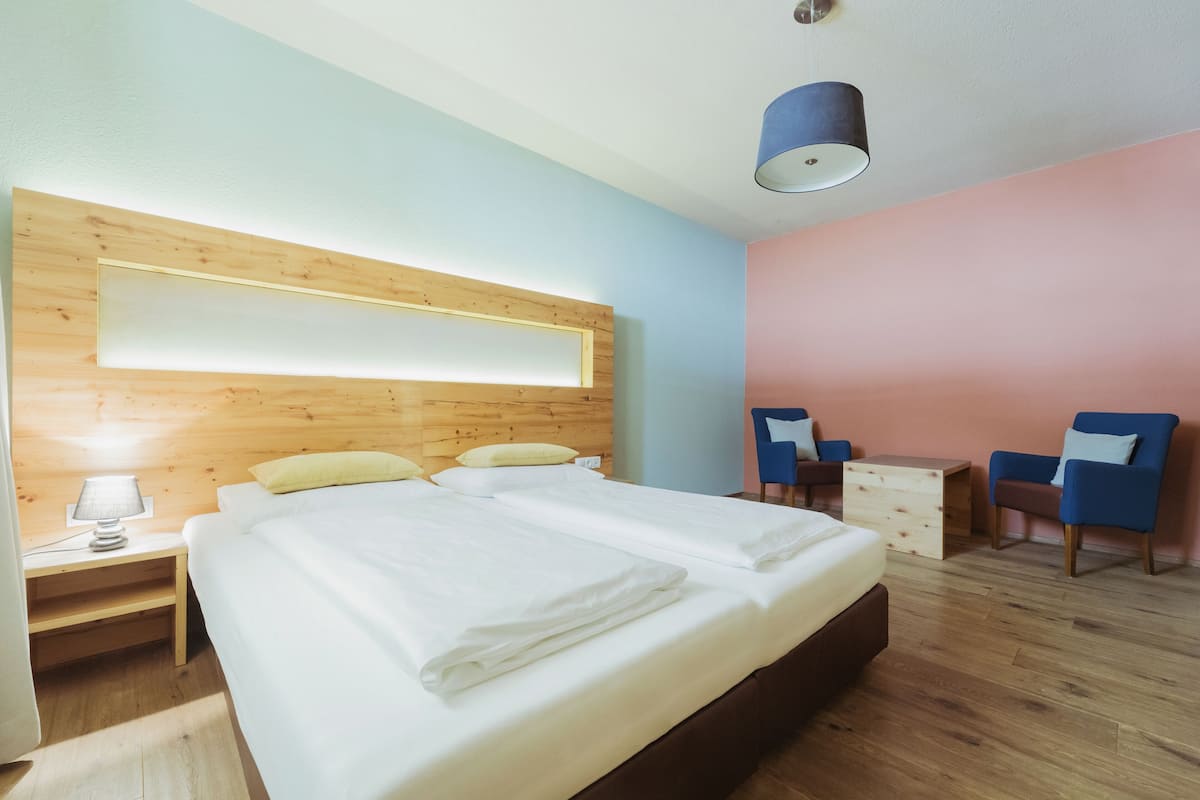 Una habitación de hotel moderna con cabecera de madera, una cama grande, un escritorio, una silla y una mesita.