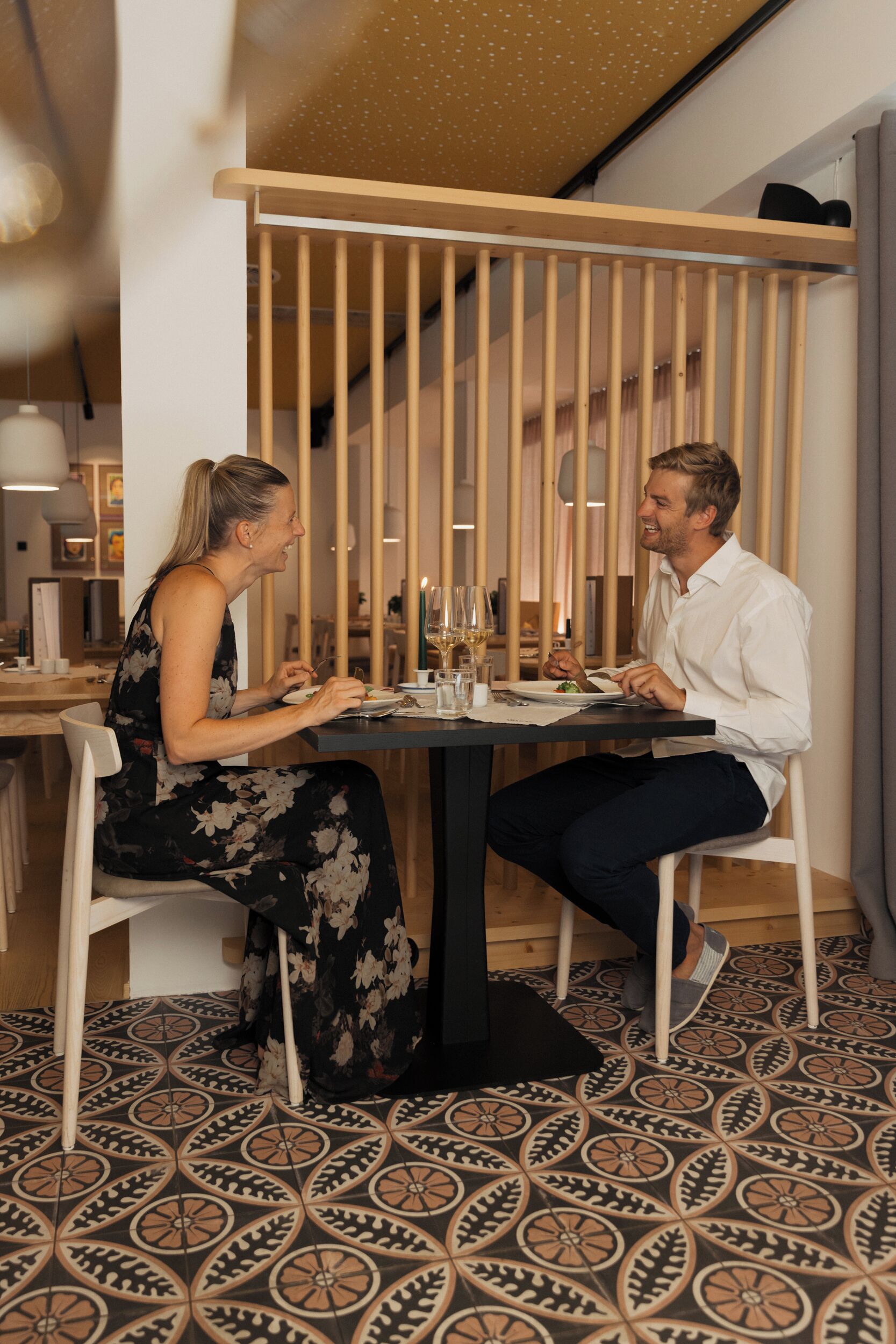 Ein Essbereich mit einer Holzwand, einem gemusterten Boden und einem Tisch für zwei Personen.