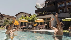 A swimming pool with lounge chairs and umbrellas. - Hotel Mari Pop (Ried im Zillertal)