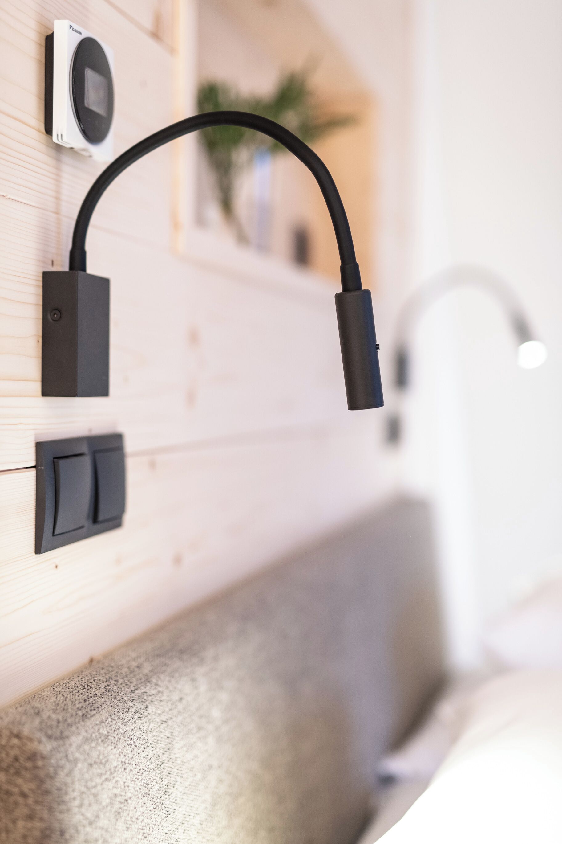 A modern bathroom with a wooden wall, a black towel rack, a towel dispenser, and a white sink.