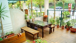 Una terraza de madera con mesa de billar, bancos y plantas en macetas.