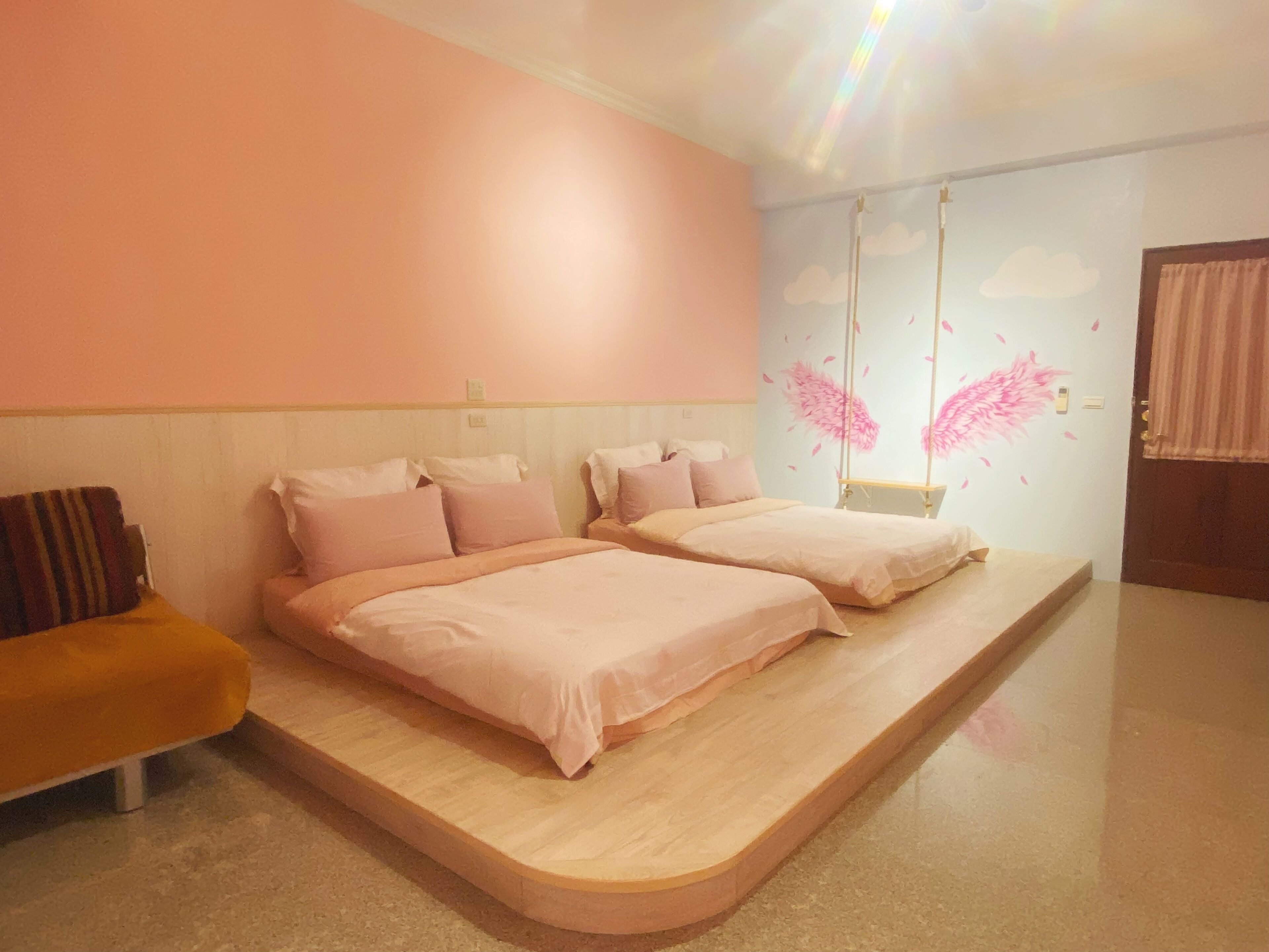 Een kamer met twee bedden, een bankje en een schommel.