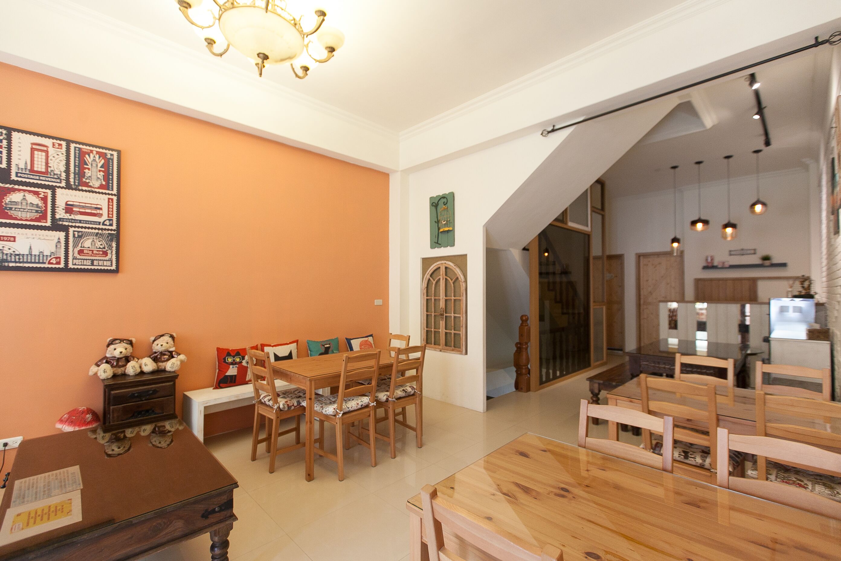 A dining area with wooden furniture, a chandelier, and a wall with postage stamp art.
