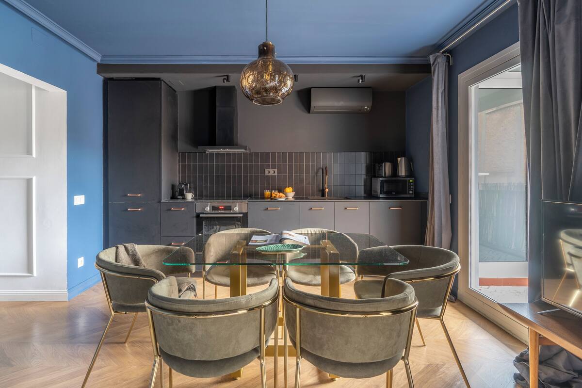 A modern kitchen with a dining area featuring a glass table and four chairs.