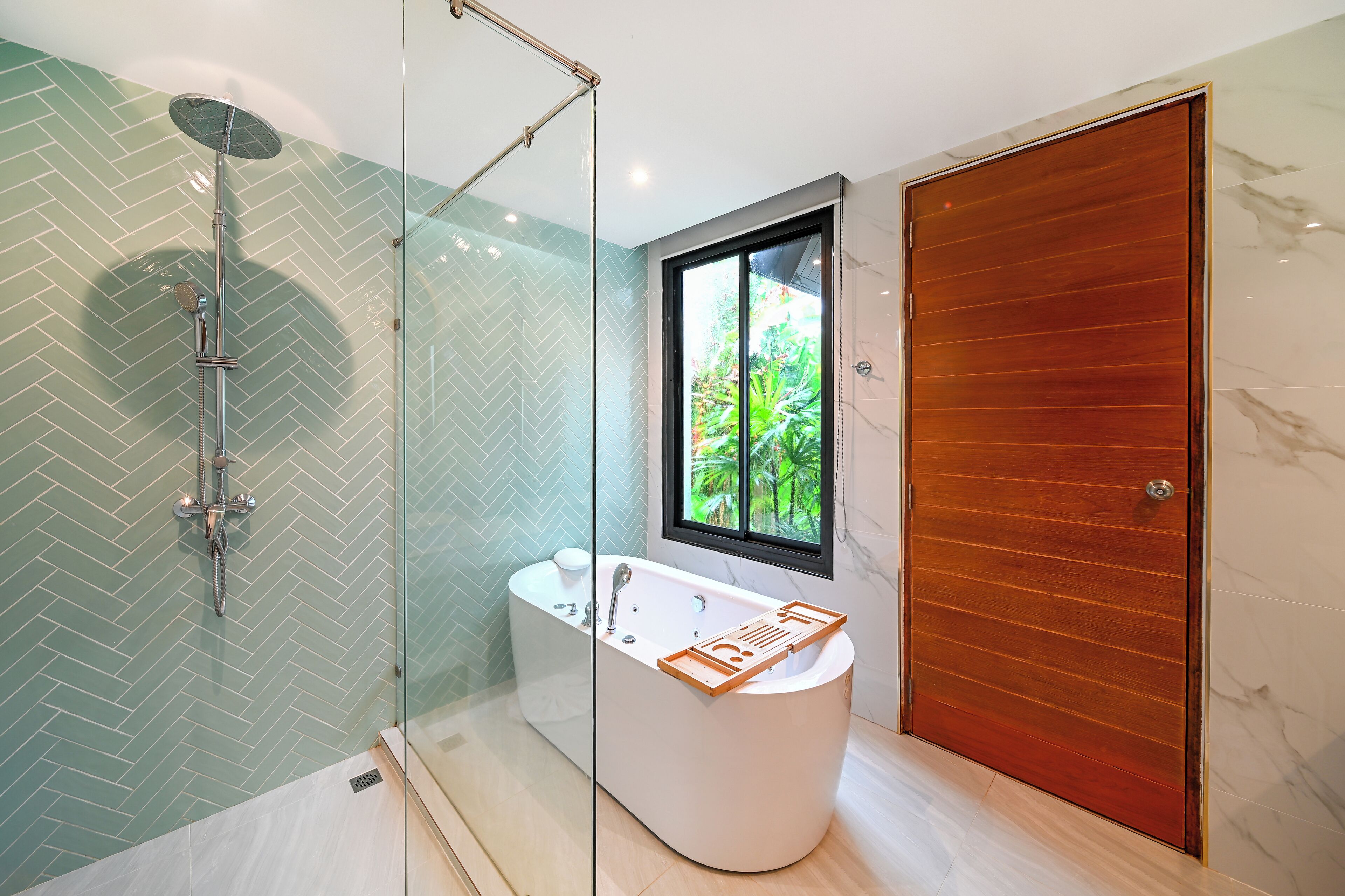 Un baño moderno con ducha envuelta en vidrio, una bañera independiente y una puerta de madera.
