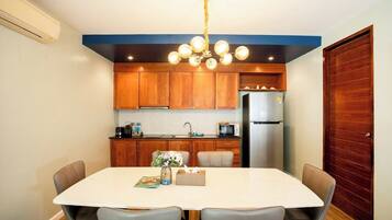 Una cocina compacta con armarios de madera, un refrigerador de acero inoxidable y una mesa de comedor con cuatro sillas.