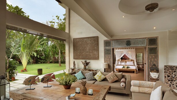 A spacious living area with a large wooden coffee table, a sofa set, and a view of a lush garden. - Villa Bali Asri Batubelig (Seminyak)