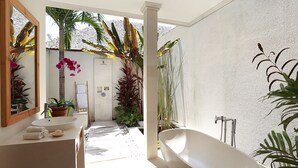A modern bathroom with a freestanding bathtub, a large mirror, and a sink. - Villa Bali Asri Batubelig (Seminyak)