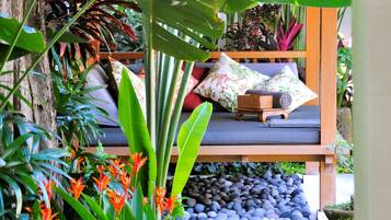 A garden with a wooden bench, tropical plants, and a stone wall.