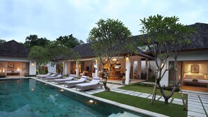 A poolside area with lounge chairs, a swimming pool, and a well-maintained lawn. - Villa Bali Asri Batubelig (Seminyak)