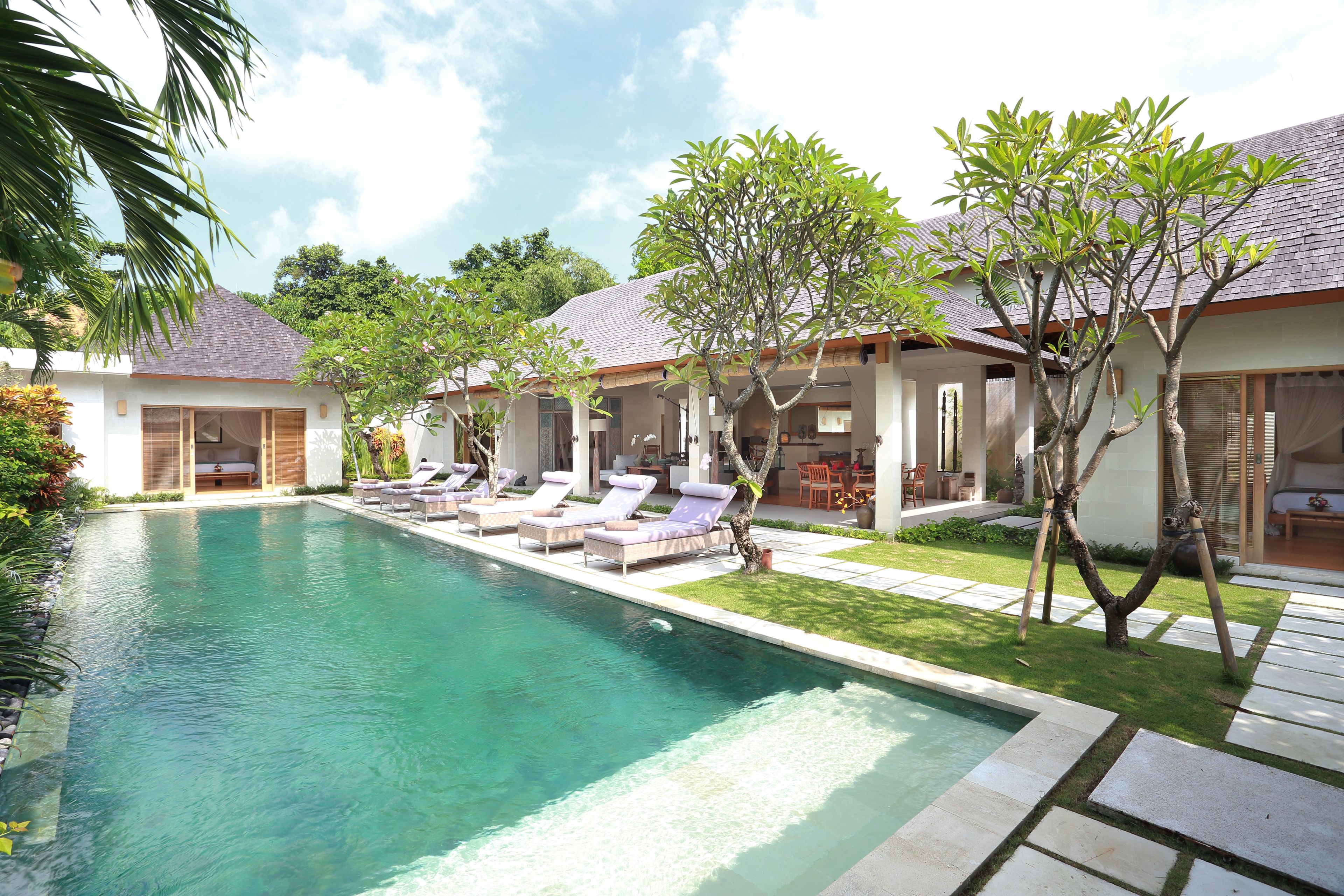 A poolside area with lounge chairs, a clear pool, and a well-maintained lawn.