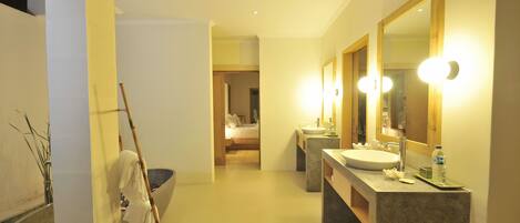 Une salle de bain moderne avec un grand miroir, deux lavabos et une baignoire.
