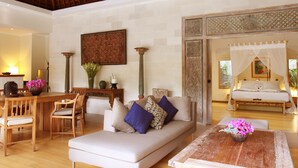 A spacious living area with a wooden dining table, a sofa with cushions, and a wooden coffee table with flowers. - Villa Bali Asri Batubelig (Seminyak)