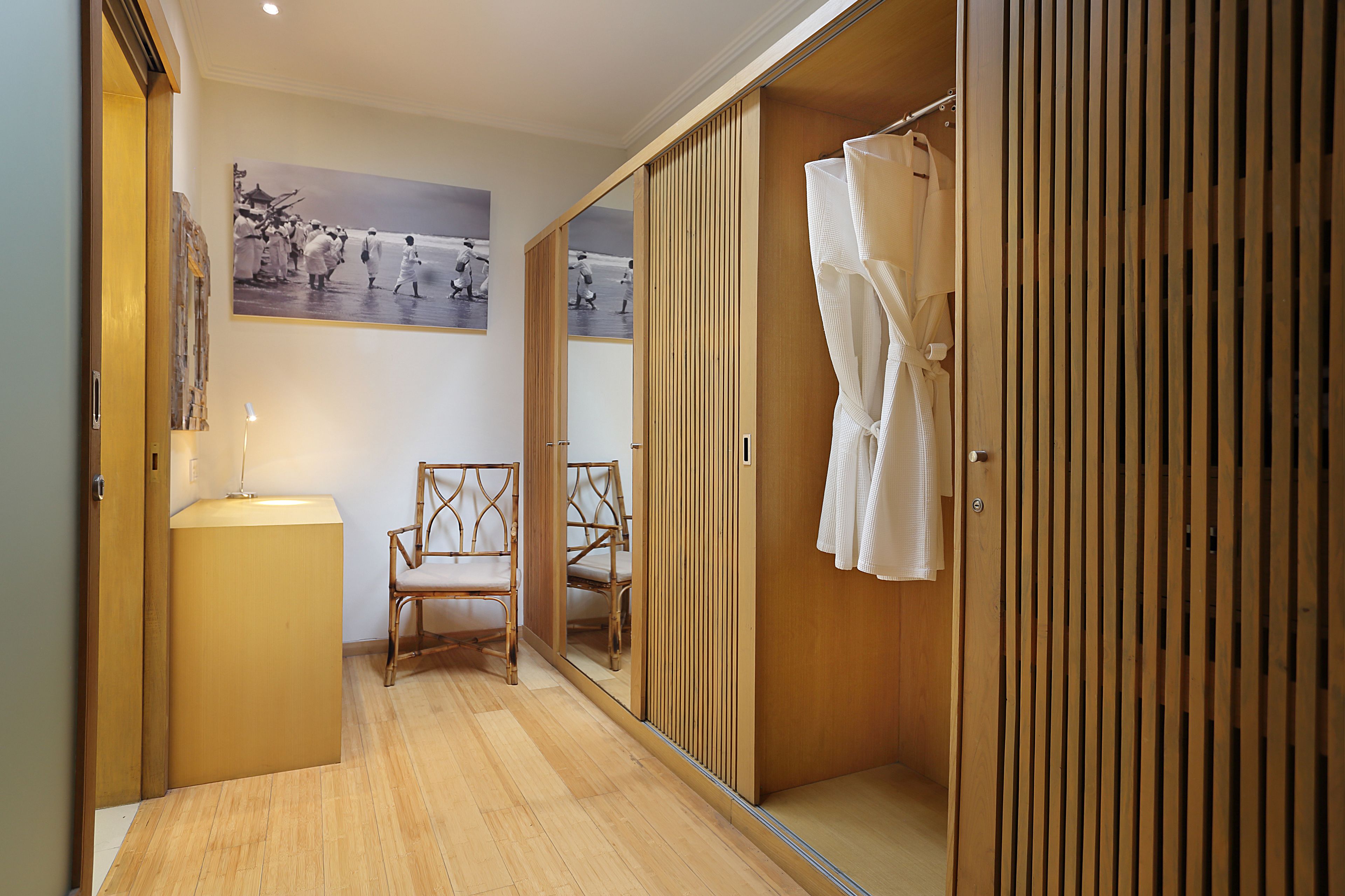 A room with a wooden floor, a chair, a mirror, and a wardrobe.