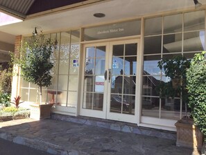 L’extérieur de l’Aberdeen Motor Inn, avec une enseigne indiquant « Chambres disponibles », de grandes fenêtres et des plantes en pot.
