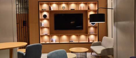 A modern living room with a flat-screen TV, built-in shelves, and comfortable seating.