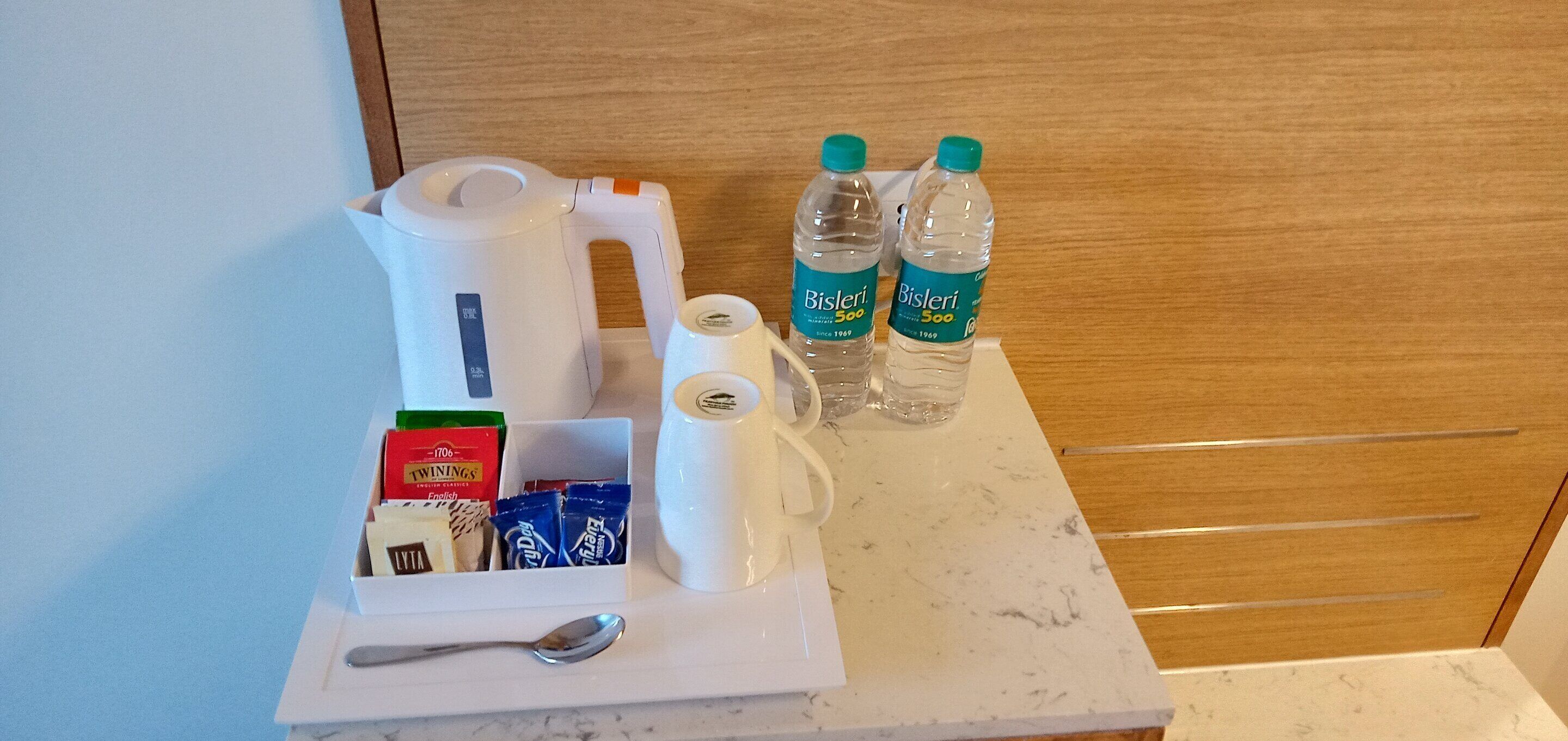 En bakke med morgenmad, inklusiv elkedel, to Bisleri vandflasker, Twinings English kaffe og Lyta mælk.