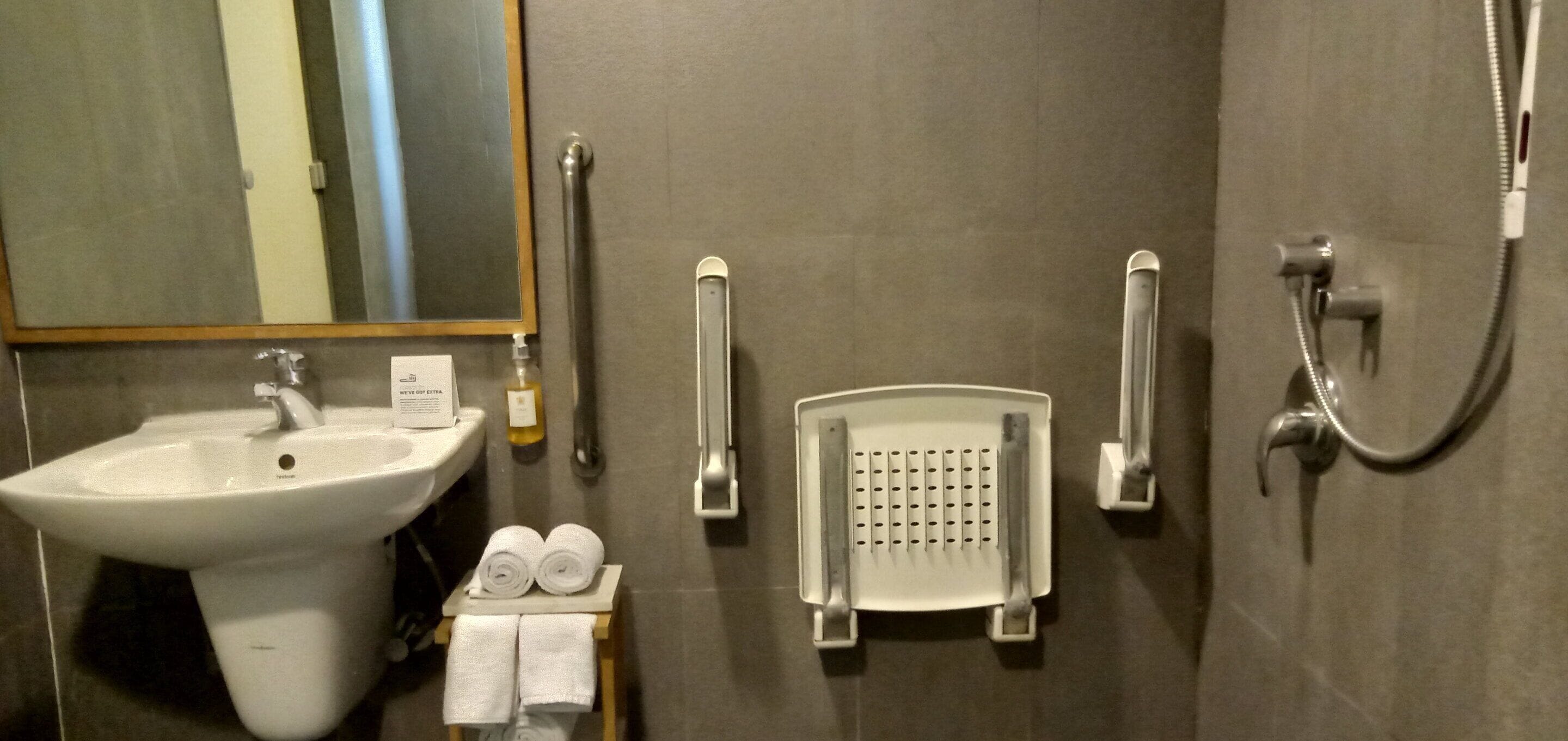 Une salle de bain équipée d’un lavabo, d’un miroir, d’une douche et d’un porte-serviettes.