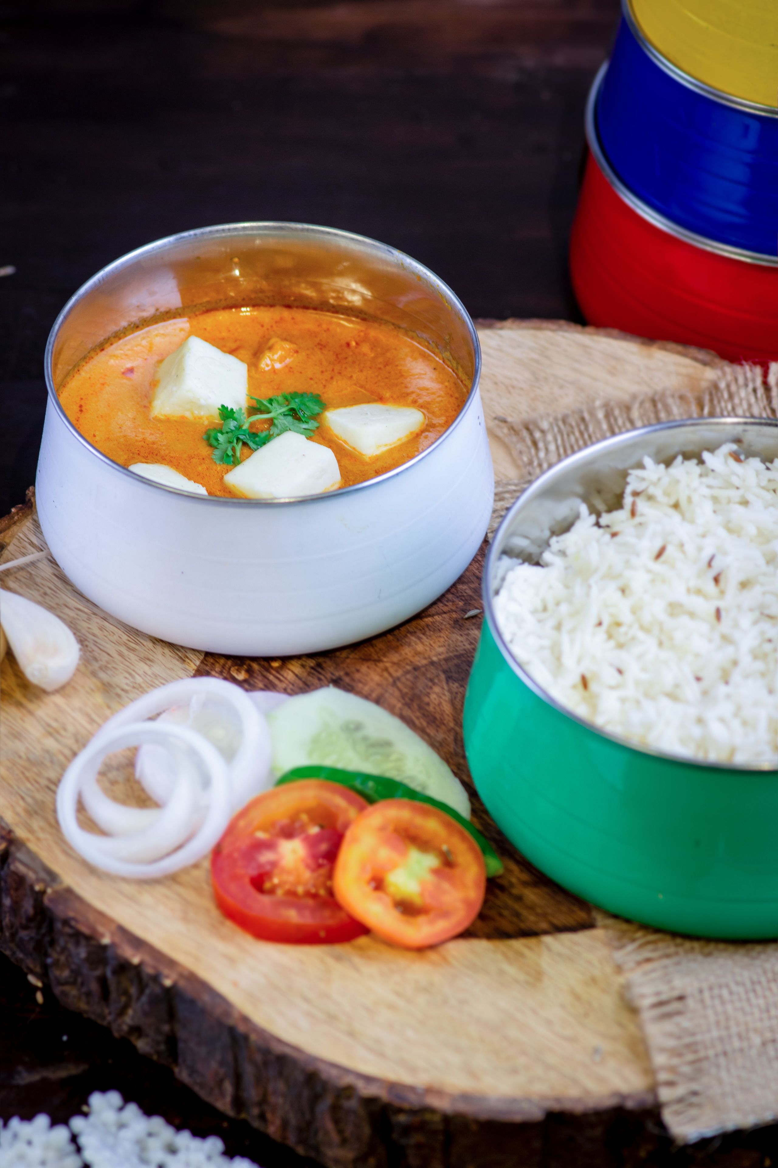 Un bol de curry accompagné de riz et de légumes, le tout présenté sur une planche en bois.