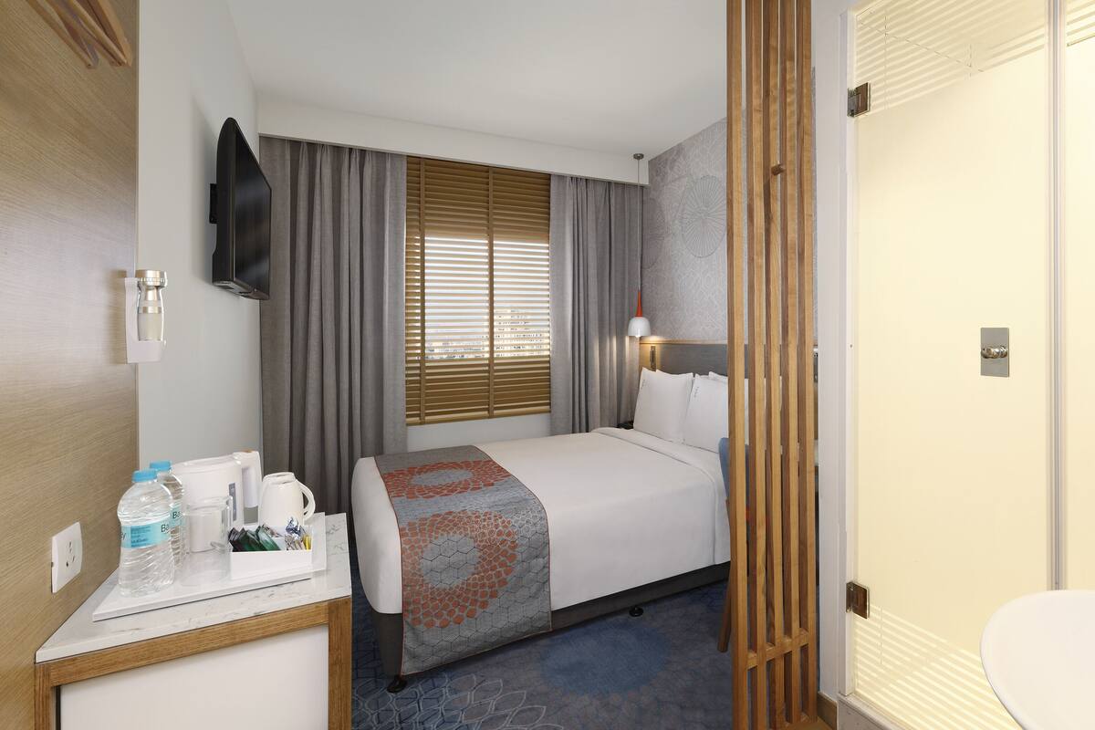 A hotel room with a bed, bedside table, and a bathroom.