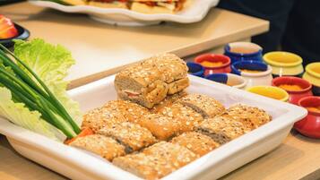 A white rectangular plate with several pieces of bread topped with seeds, accompanied by a side of green lettuce and green onions.