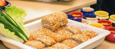 A white rectangular plate with several pieces of bread topped with seeds, accompanied by a side of green lettuce and green onions.