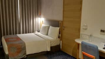 Una habitación de hotel con una cama, un escritorio y una silla.