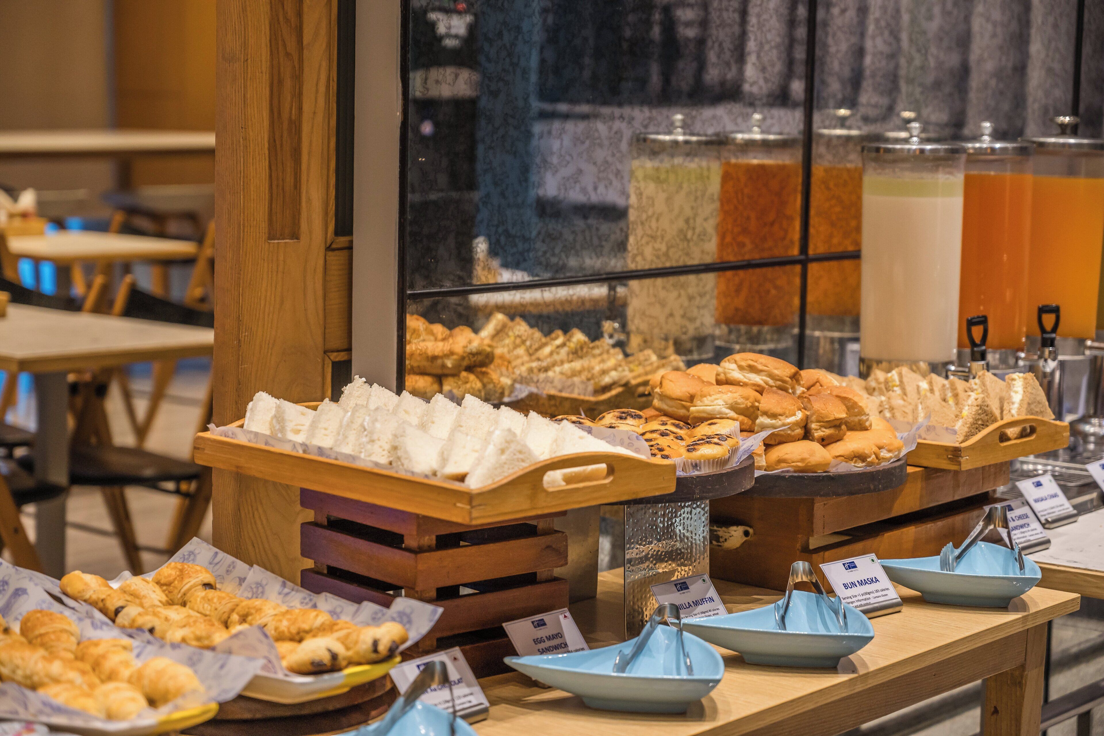 Un buffet de petit-déjeuner proposant diverses viennoiseries et pains présentés sur des présentoirs en bois.