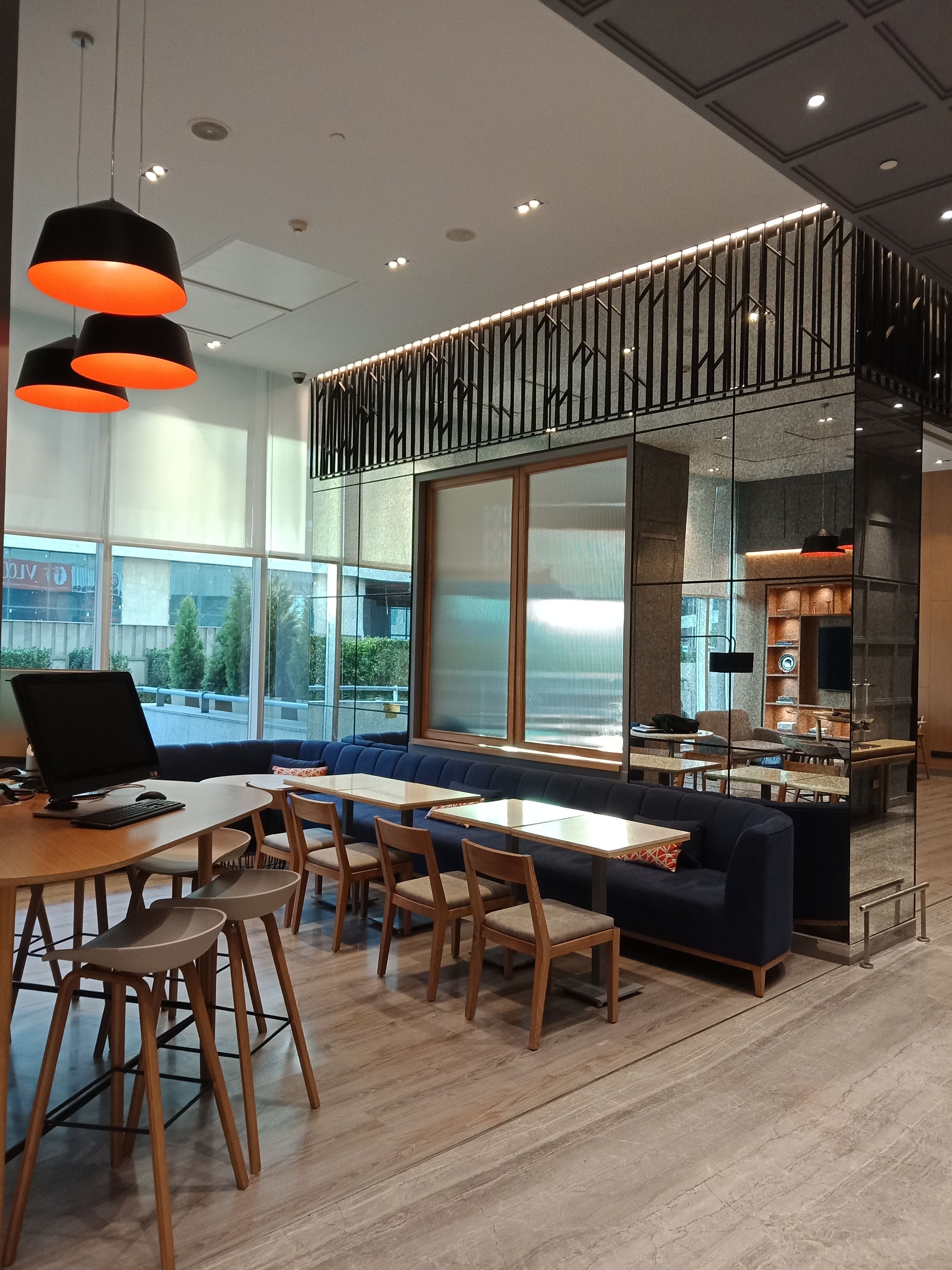 A modern dining area with a long wooden table, several chairs, and a blue sofa.