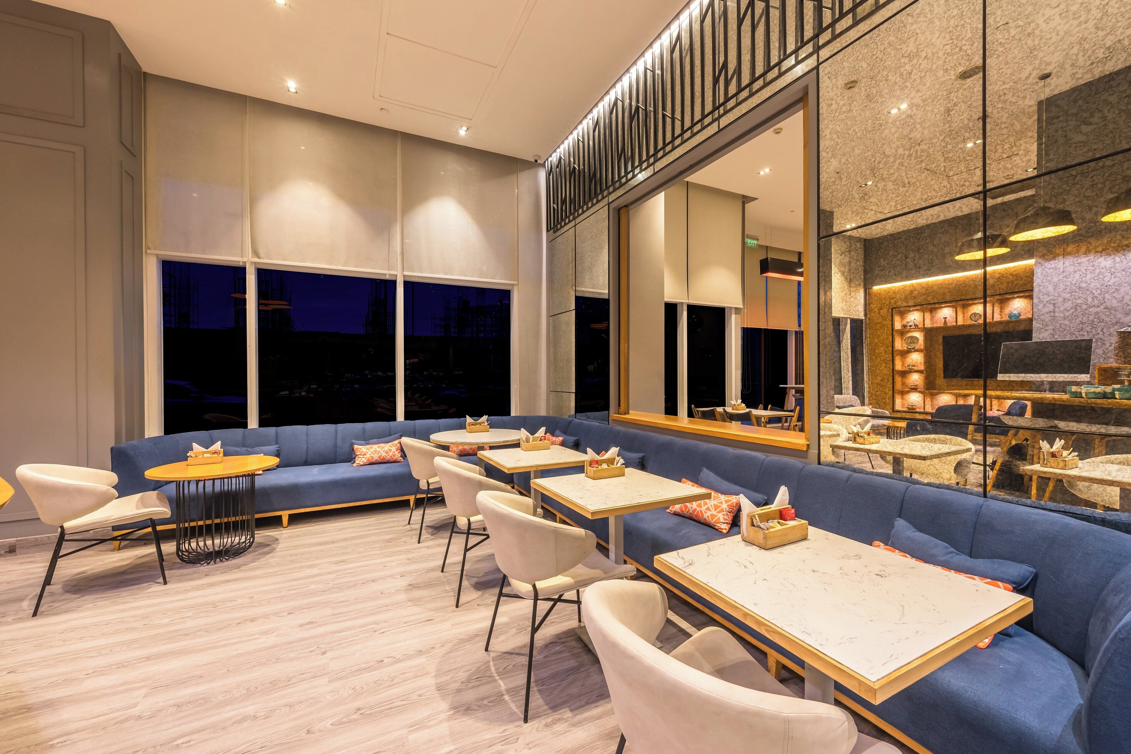A modern restaurant with a blue sofa, white chairs, and round tables.