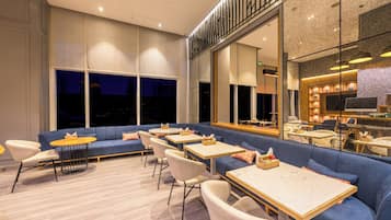A modern restaurant with a blue sofa, white chairs, and round tables.
