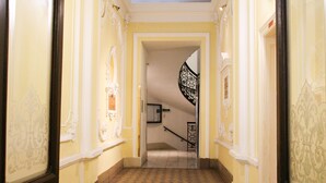 A hallway with ornate wall decorations, a patterned carpet, and a staircase with a decorative railing. - City Pension Stephansplatz I Self Check In (Vienna)
