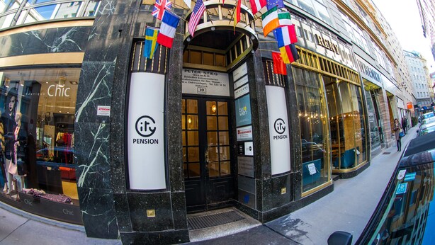 A building with a black marble facade, a sign for 'Pension', and multiple flags. - City Pension Stephansplatz I Self Check In (Vienna)