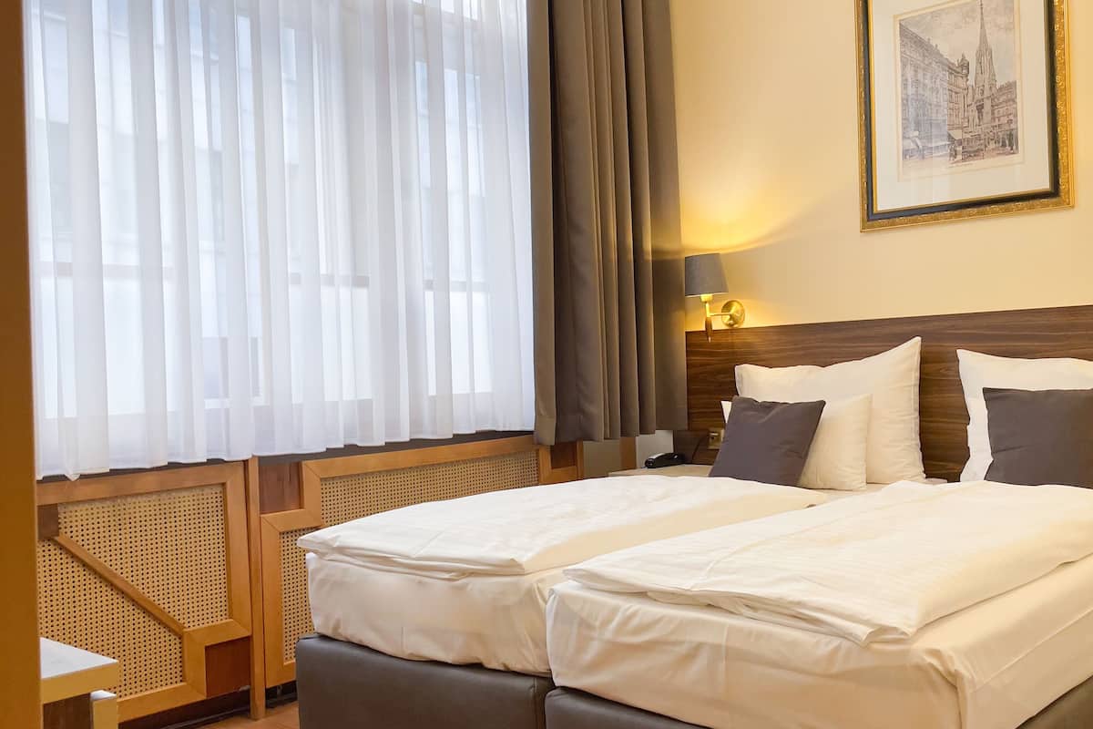 Una cama doble con ropa de cama blanca, un cabecero de madera y una mesita de noche con lámpara.