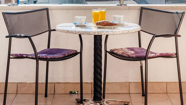 A balcony with a table and two chairs, overlooking a coastal view. - Apartments Vila Adrijana and Fitness Studio Wolf (Baska Voda)