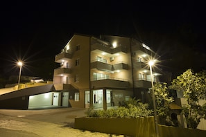 En byggnad med flera våningar, balkonger, en entré i markplan och en parkeringsplats.