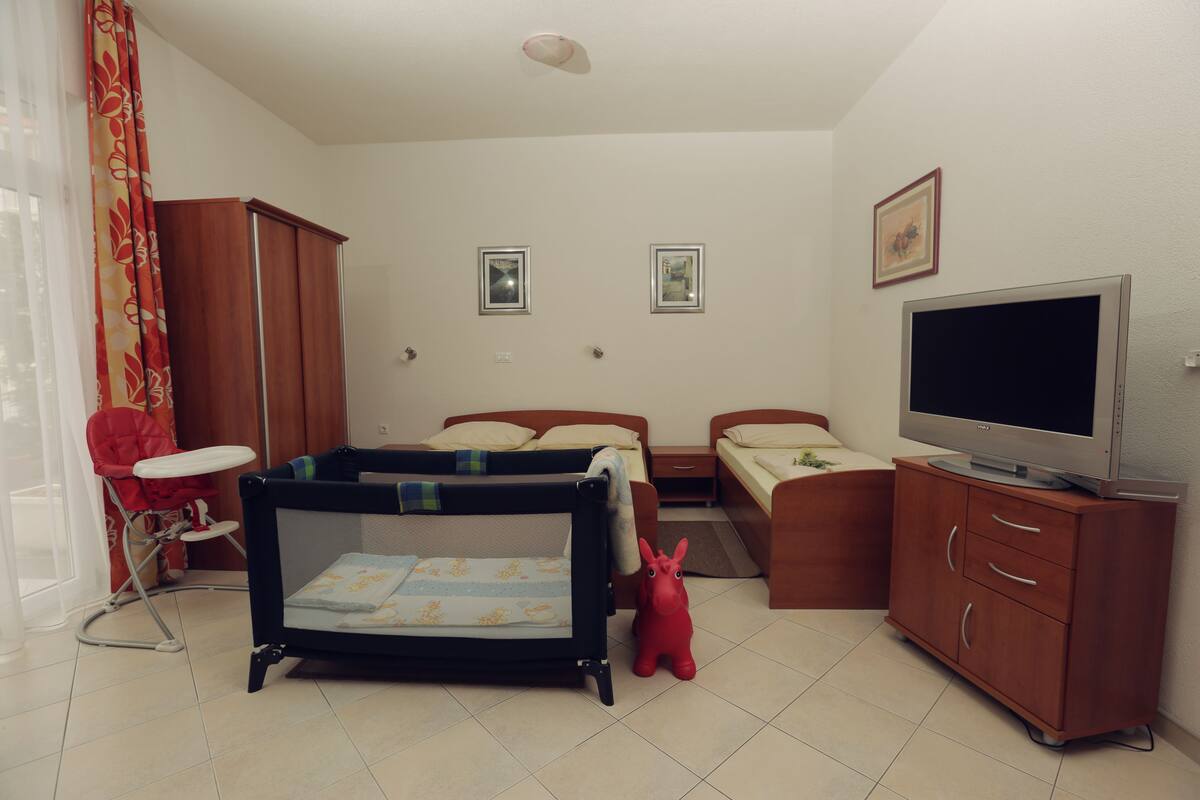 Ein Schlafzimmer mit einem Bett, einem Fernseher, einem Kleiderschrank und einem Babybett.