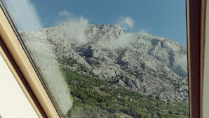 A mountainous landscape with rocky terrain and sparse vegetation, viewed through a window. - Apartments Vila Adrijana and Fitness Studio Wolf (Baska Voda)