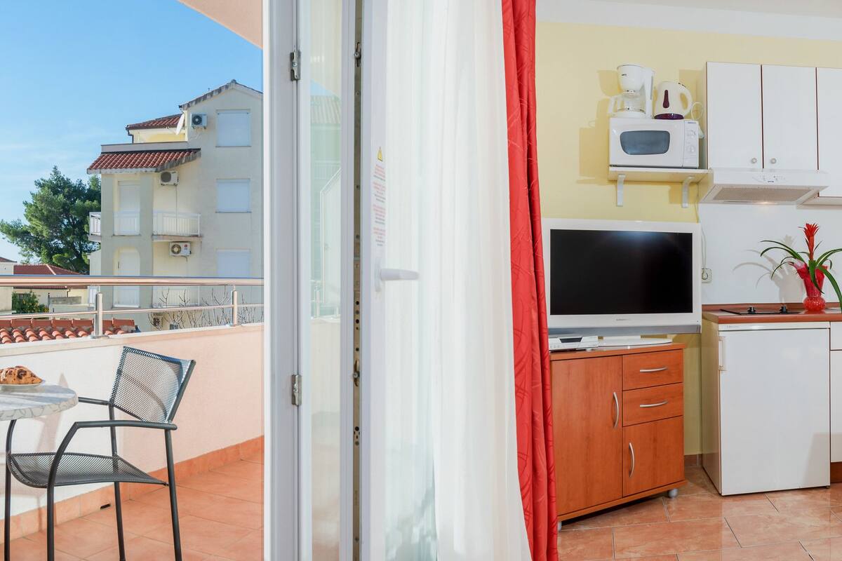 Eine kompakte Küche mit Essbereich, einem kleinen Tisch mit Stühlen und Blick auf den Balkon.