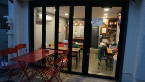 A restaurant with a red table and chairs outside, a glass door entrance, and a visible interior with tables and chairs inside. - Zzzip Guest House - Hostel (Seoul)