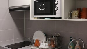 A kitchen with a microwave, sink, and cabinets. - Zzzip Guest House - Hostel (Seoul)